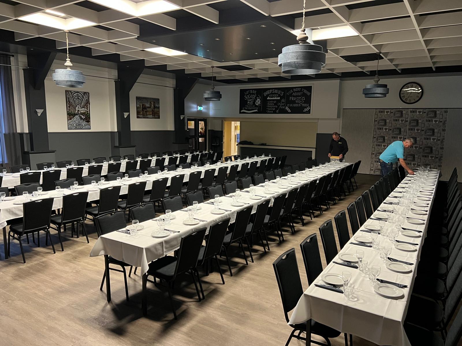 Lange gedekte tafels in de grote zaal van het Dorpshuis Hierden.